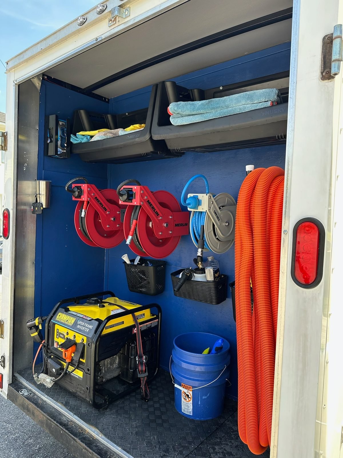Inside the Dagger Shine mobile detailing trailer. Hose reels, generator, supplies.